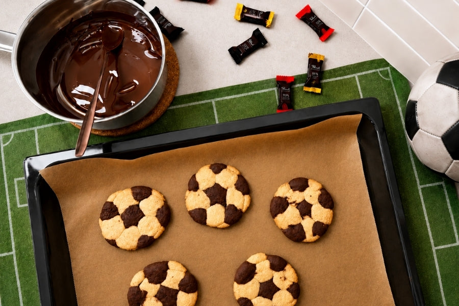 Fußballplatz-Tischdekoration mit gebackenen Fußball-Muster-Cookies und geschmolzener Schokolade in einem Topf.