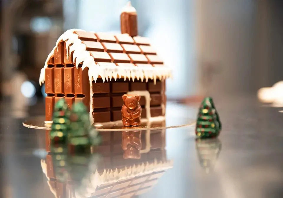 Schokoladenhaus mit Schneedecke, Tannenbäume und Bär aus Schokolade.