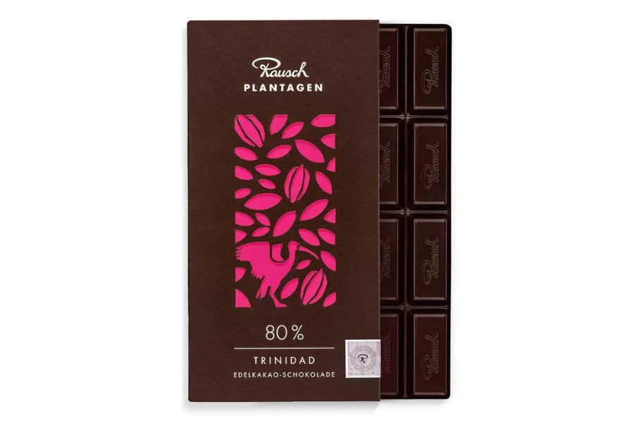 Rausch Trinidad 80% Edel-Kakao-Schokolade mit lila Blatt- und Kakaomotiv auf der Verpackung vor Schokoladentafel.