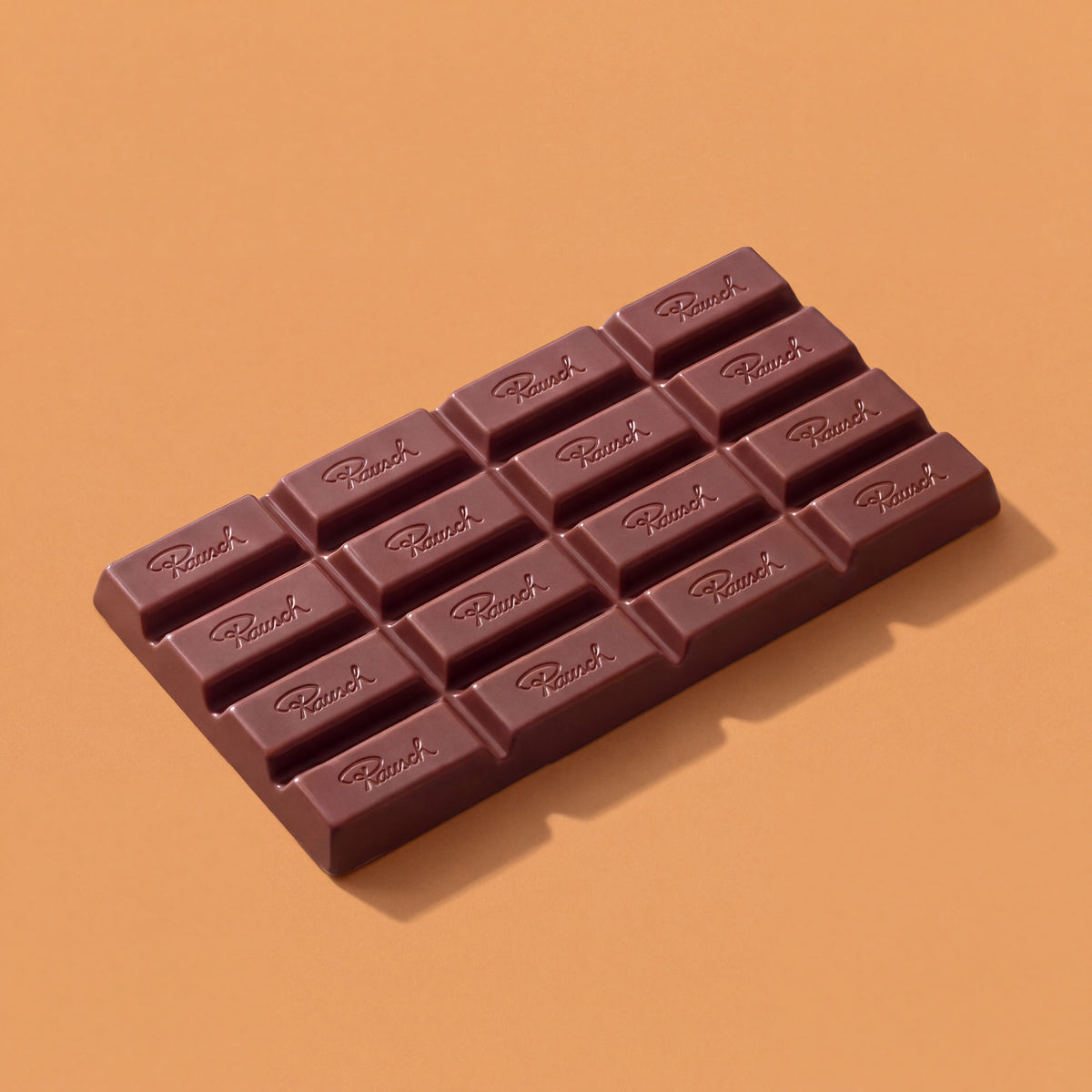 Handwerkliche braune Schokoladentafel mit eingeprägten Segmenten auf orangefarbenem Hintergrund. - Rausch