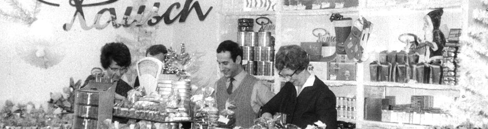 Historisches Foto eines Rausch-Schokoladengeschäfts mit Mitarbeitenden, umgeben von Schokolade und Dekorationen.