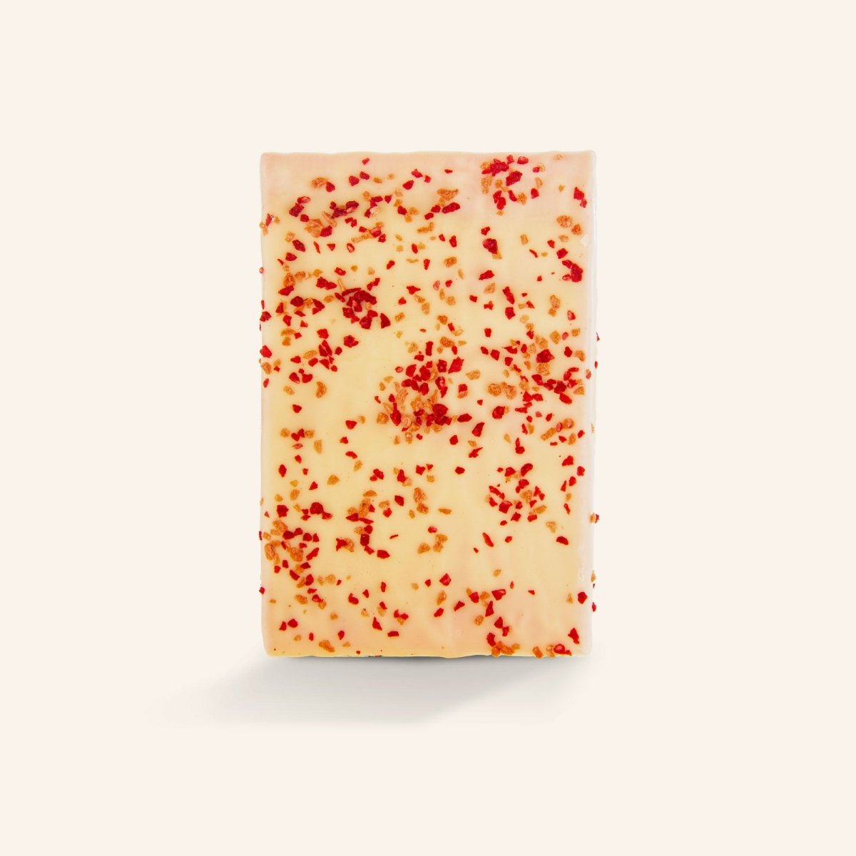 Weiße Schokoladentafel mit kleinen Erdbeer- und Himbeerstückchen auf hellem Hintergrund.