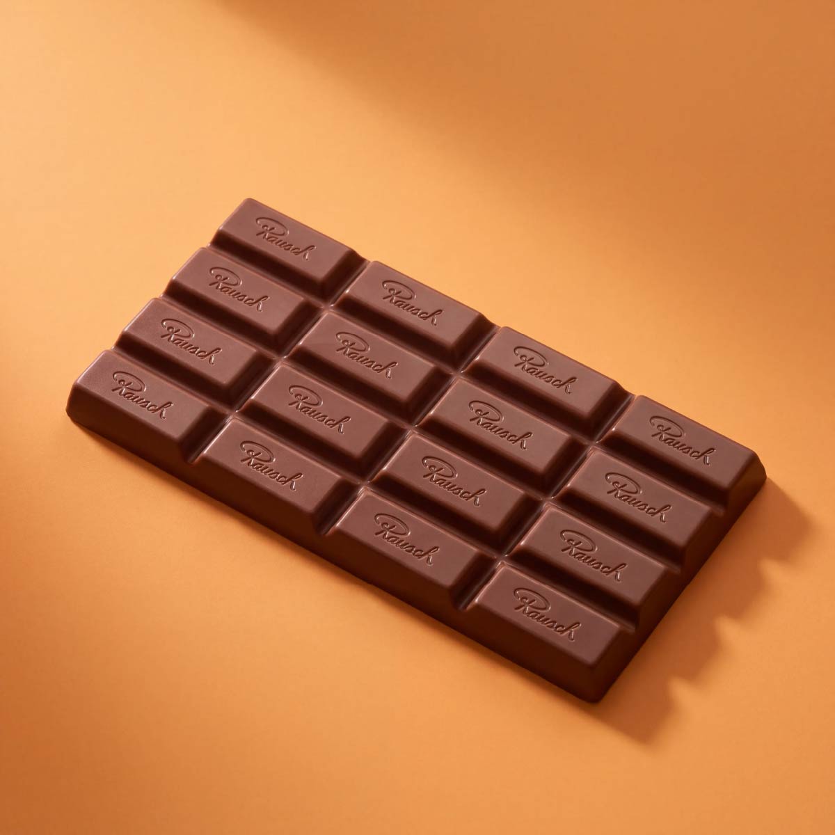 Handwerkliche braune Schokoladentafel mit eingeprägten Segmenten auf orangefarbenem Hintergrund. - Rausch