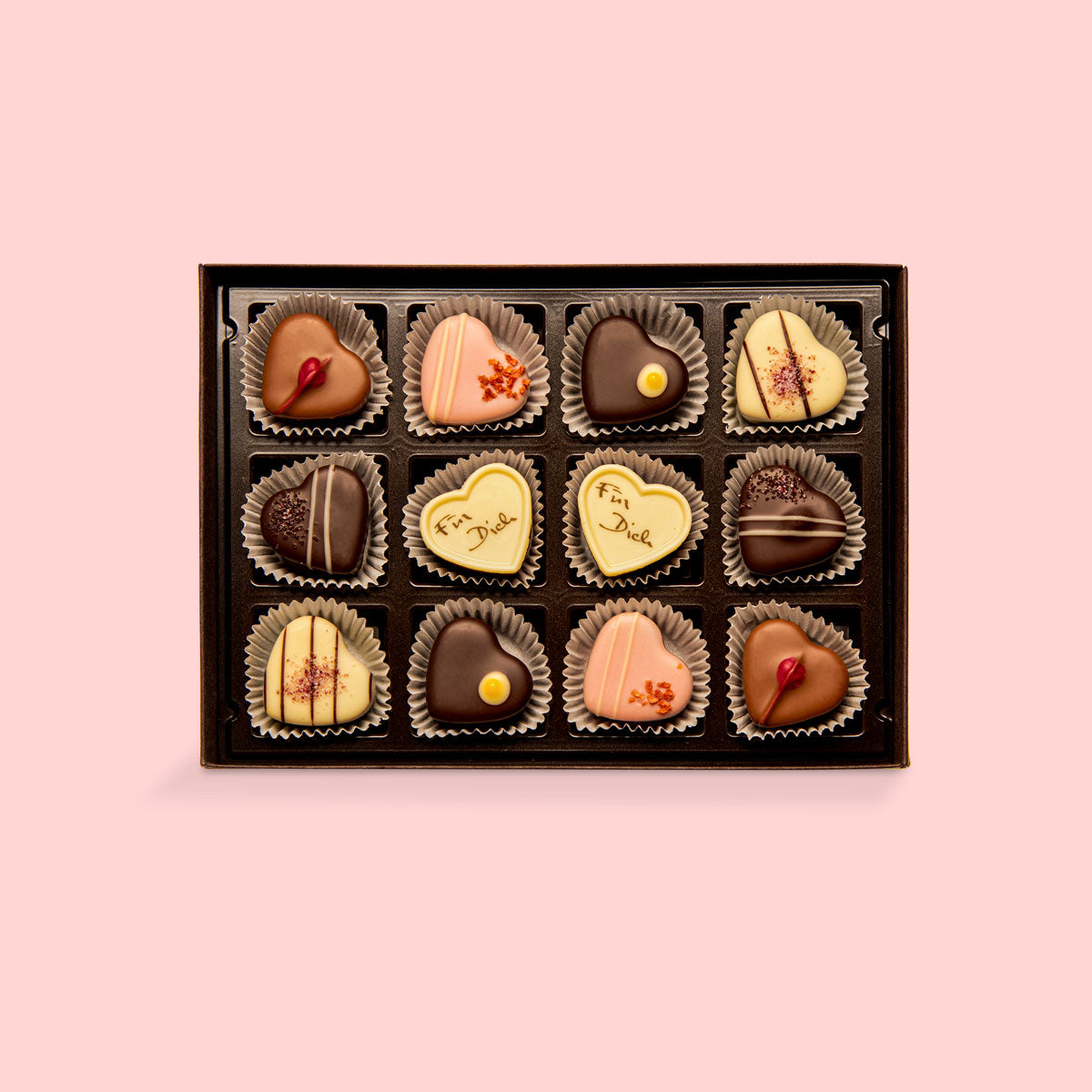 Offene Schachtel mit Herzpralinen in verschiedenen Schokoladensorten und Dekoration.