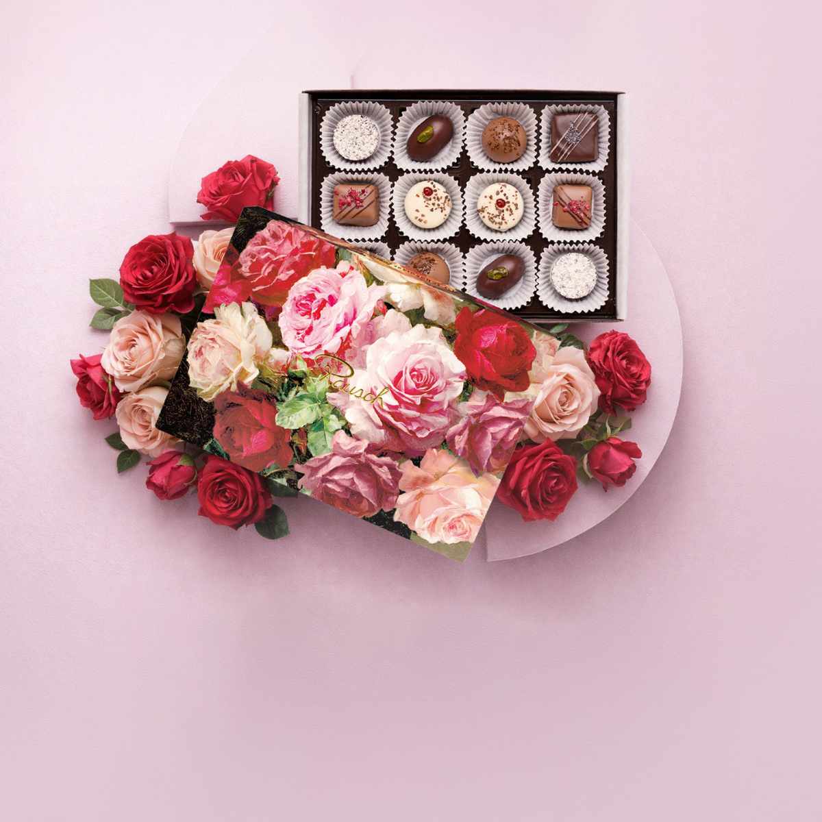 Pralinenbox mit Rosenmuster und roten, rosa Rosen auf rosa Hintergrund, Muttertagsmotiv.