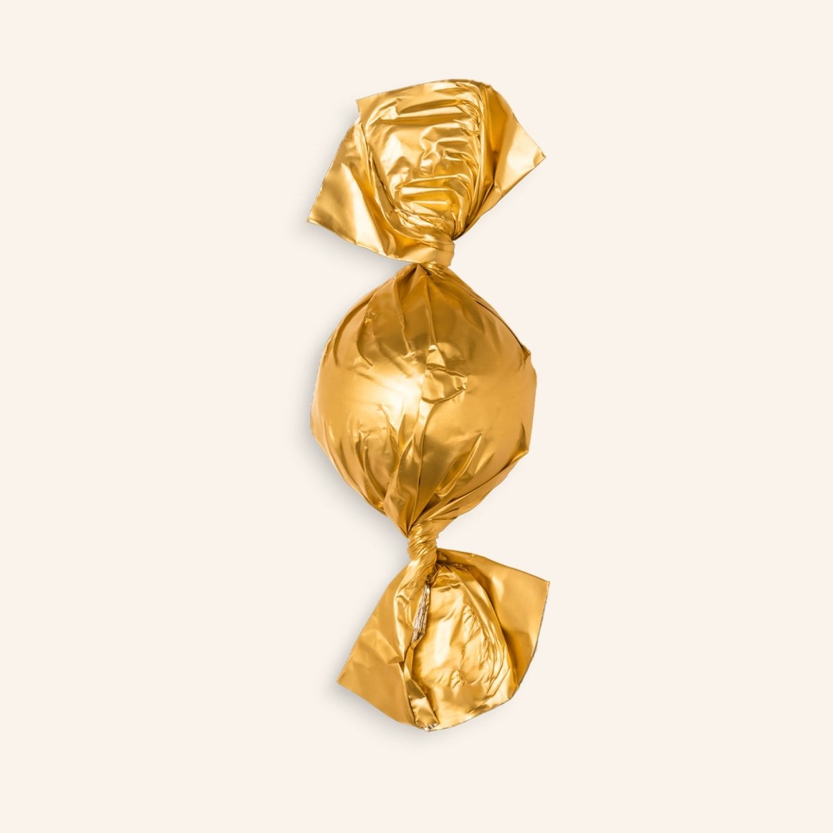 Golden-verpackte Pralinenkugel vor beigem Hintergrund.