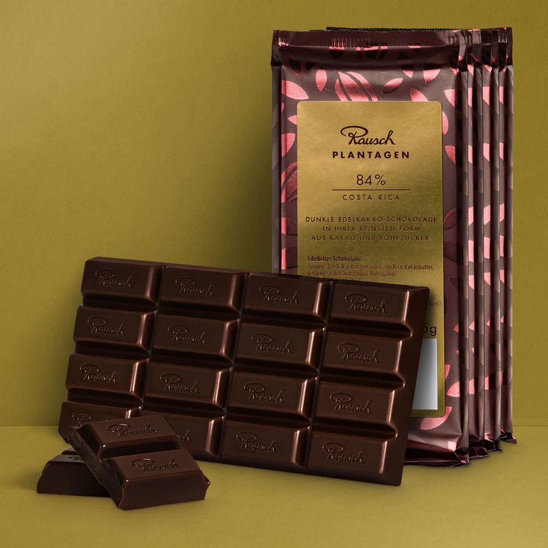 Bundle aus Rausch Plantagen Costa Rica 84% Schokolade auf goldenem Hintergrund.