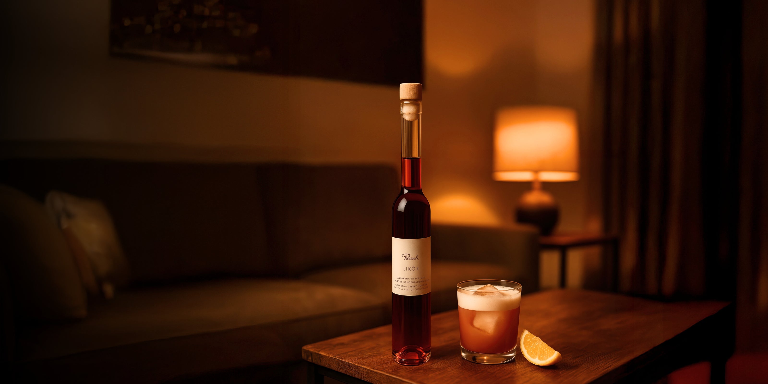 Eleganter Likör mit Cocktail und Zitronenscheibe auf einem Tisch, im Hintergrund gemütliche Wohnzimmerbeleuchtung.